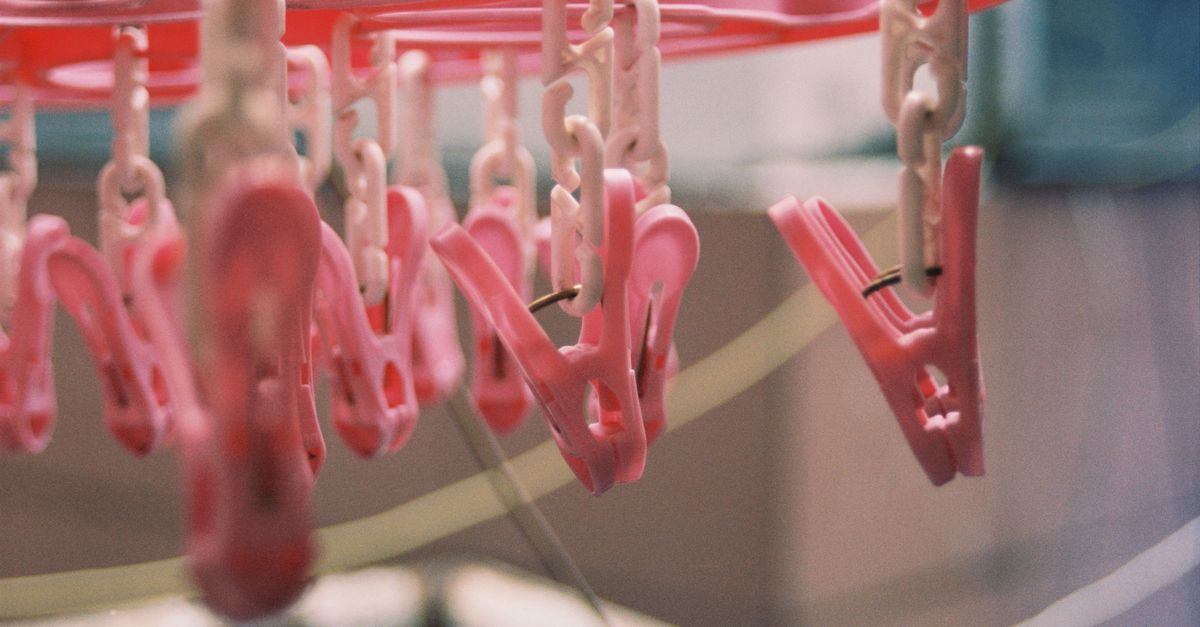 Varal de plástico com prendedores de roupa cor-de-rosa e branco pendurados, vazio, aguardando as roupas.