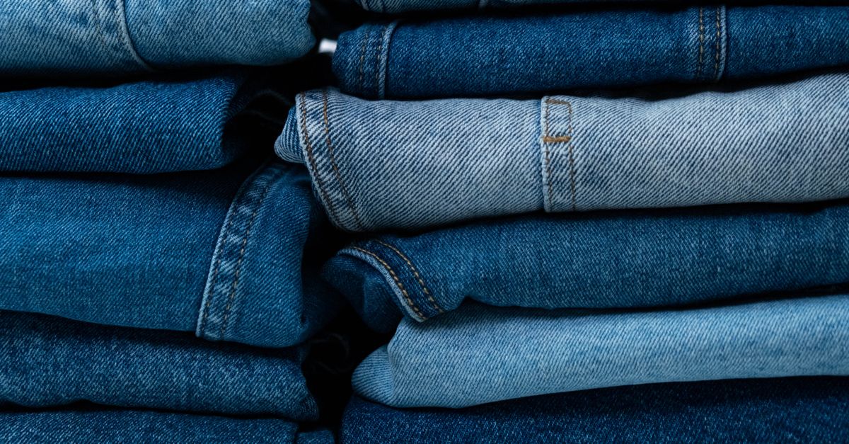 Pilha de calças jeans dobradas em tons variados de azul, organizadas uma sobre a outra.