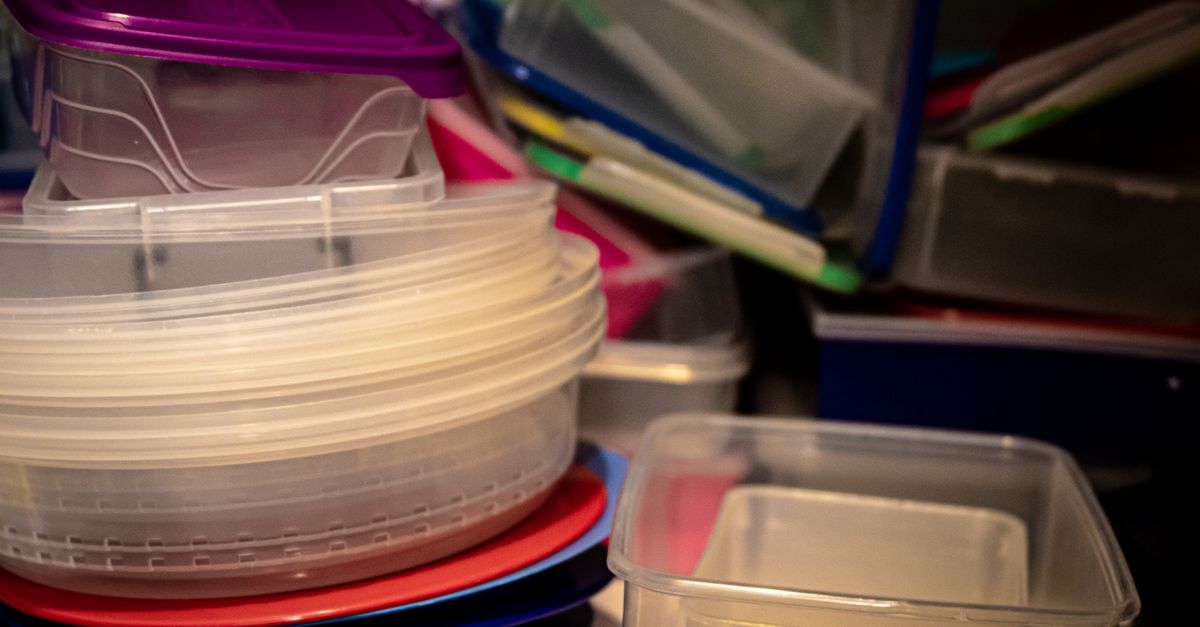 Pilha de potes e caixas plásticas transparentes empilhados em um armário de cozinha
