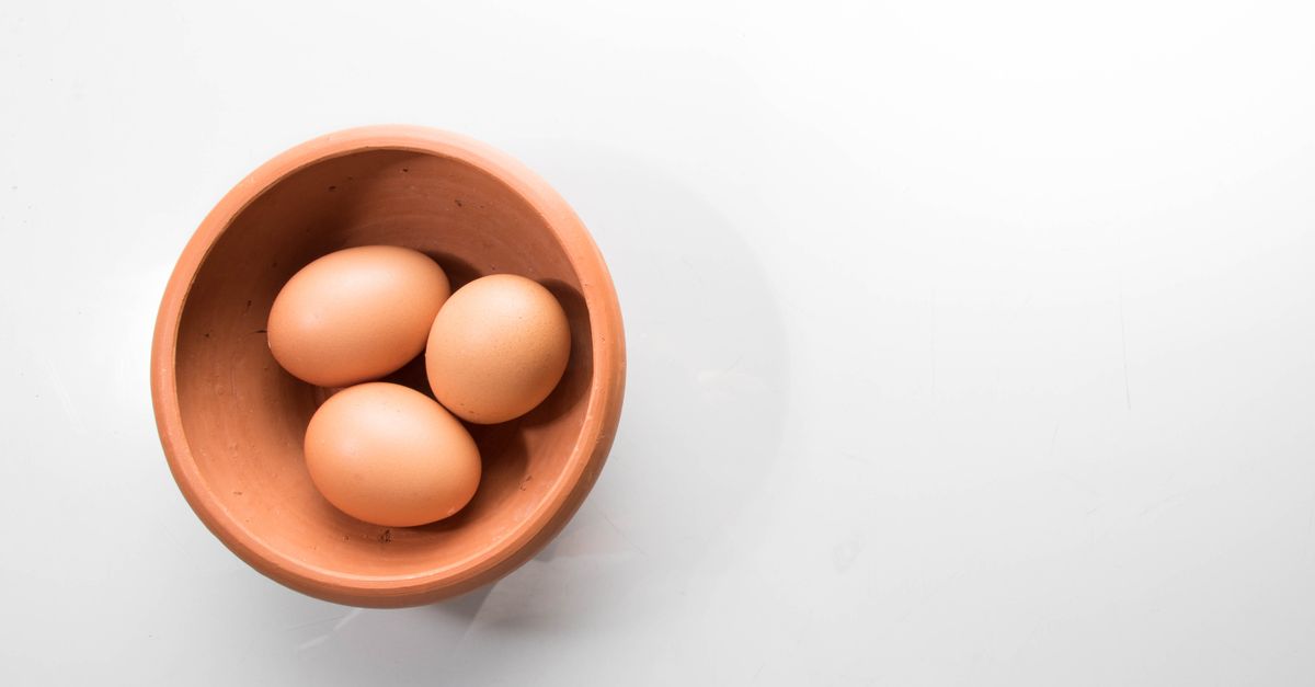 Três ovos marrons dispostos dentro de uma tigela de cerâmica sobre fundo branco.
