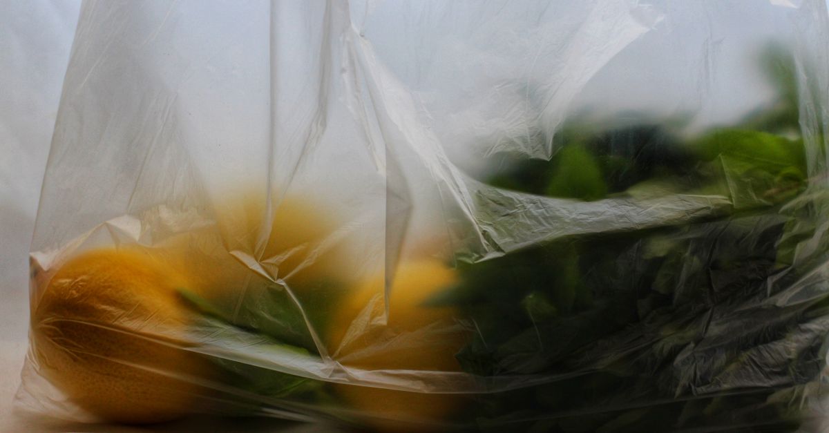 Limões inteiros dentro de um saco plástico transparente, junto com folhas verdes.