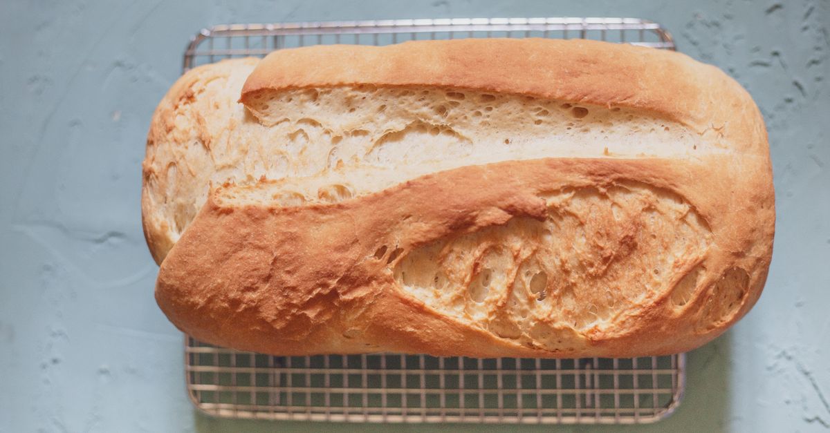 Pão de forma dourado e assado, recém-saído do forno, repousando sobre uma grade de resfriamento.